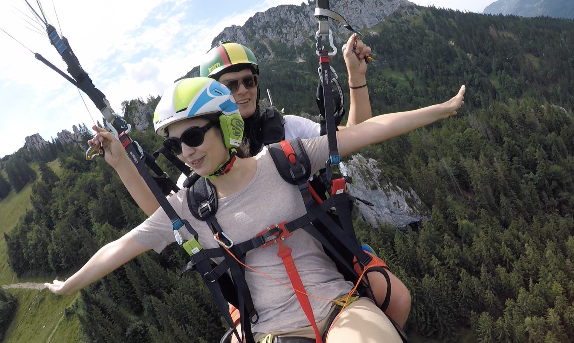 Tandempassagierin mit ausgebreiteten Armen über den Chiemgauer Alpen